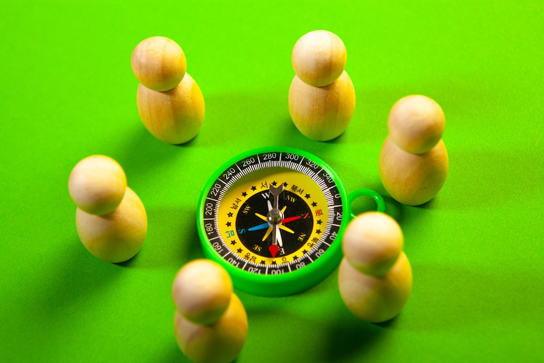 Wooden figures surround a green compass on a green surface