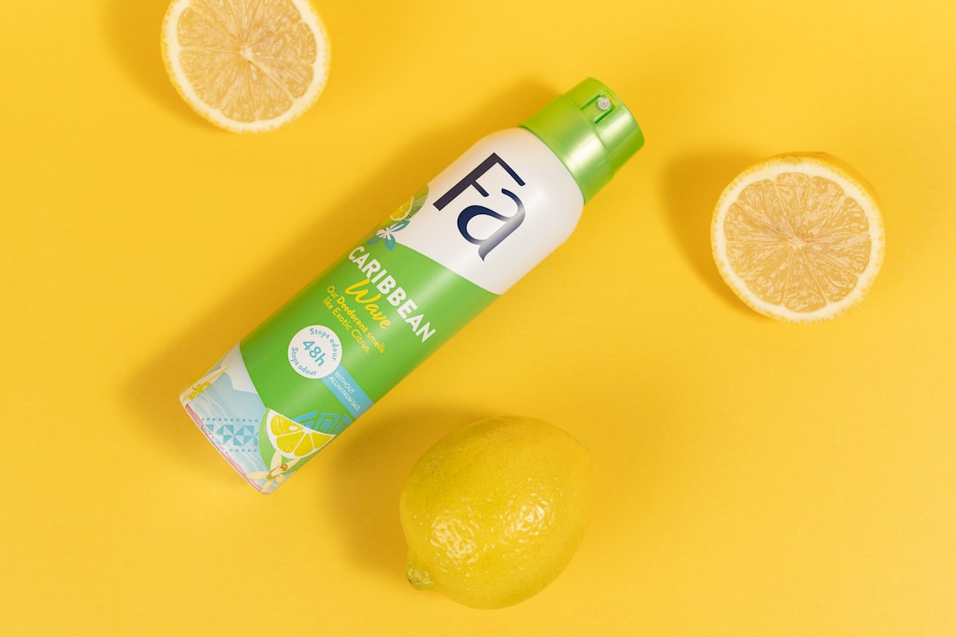 A tube of deodorant next to lemons on a yellow background