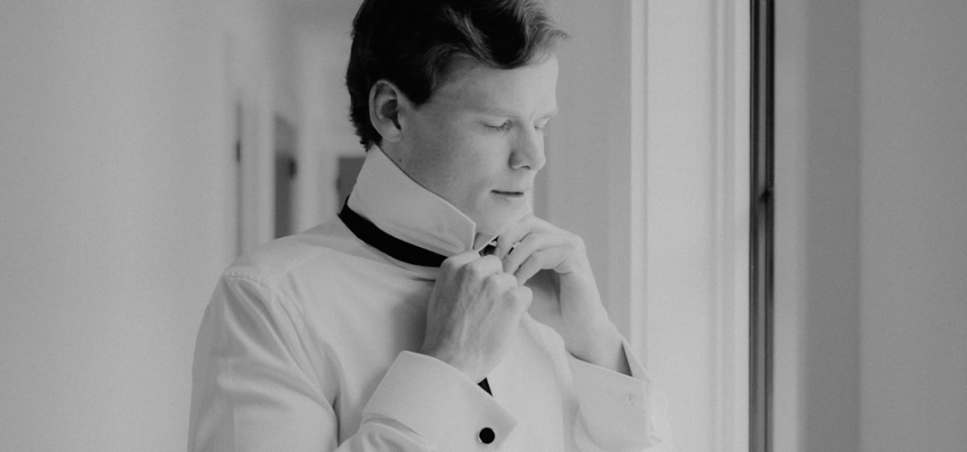 a man in a white shirt adjusting his tie