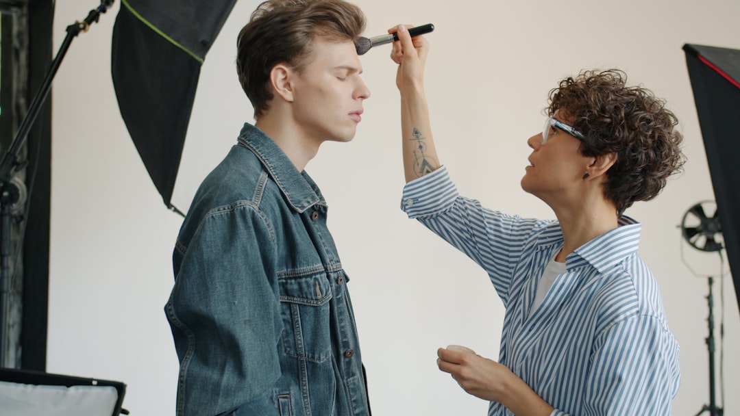 Makeup artist applying makeup to a male model.
