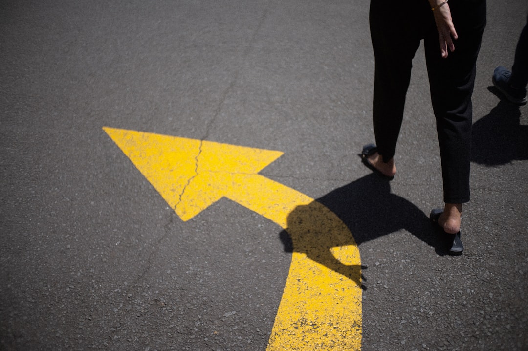 a person walking across a yellow arrow painted on the road