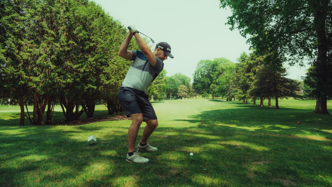 A golfer is swinging his club on the course.