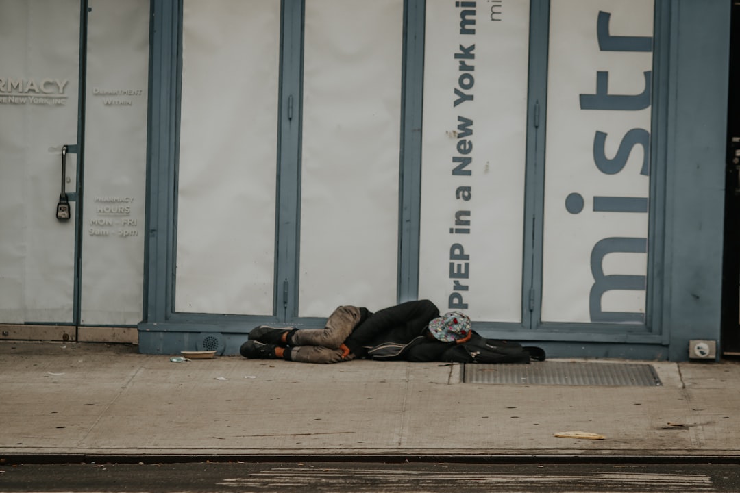 a homeless man sleeping on the sidewalk in front of a building